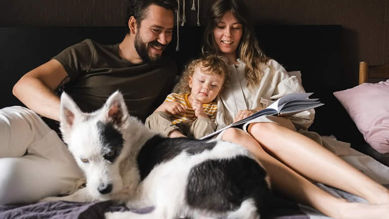 mom, dad, child and dog laying on a bed